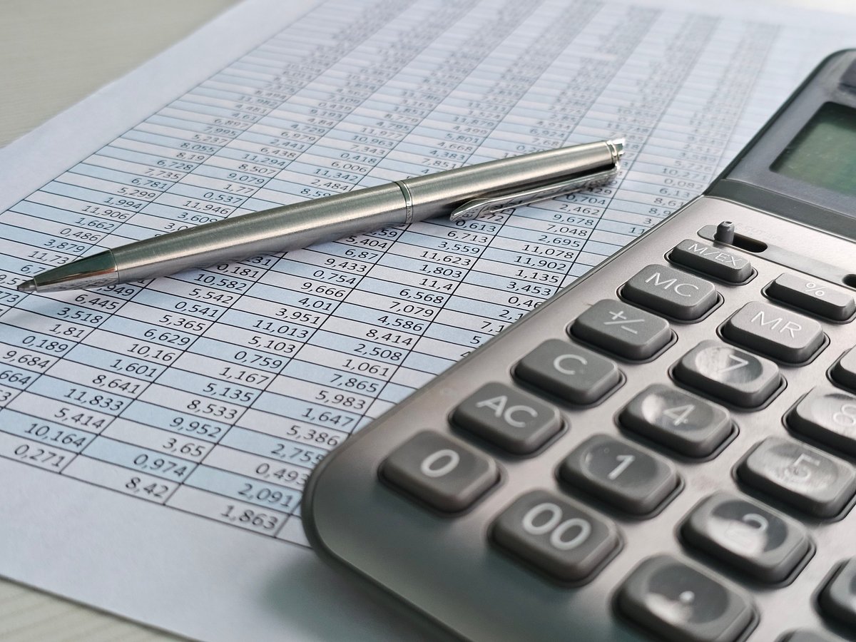 Detailed financial calculations on a sheet of paper beside a calculator and a pen in a well-lit office setting