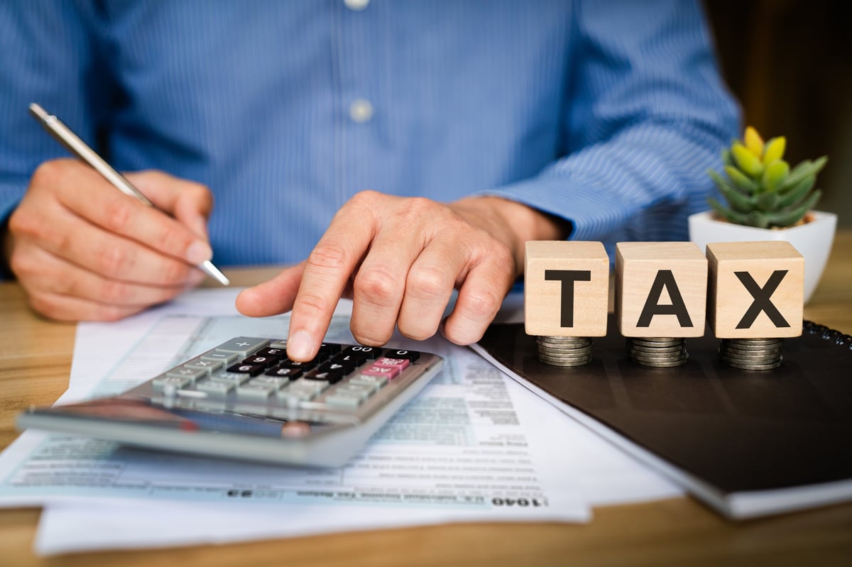 Business professional calculating tax with calculator and pen on financial documents